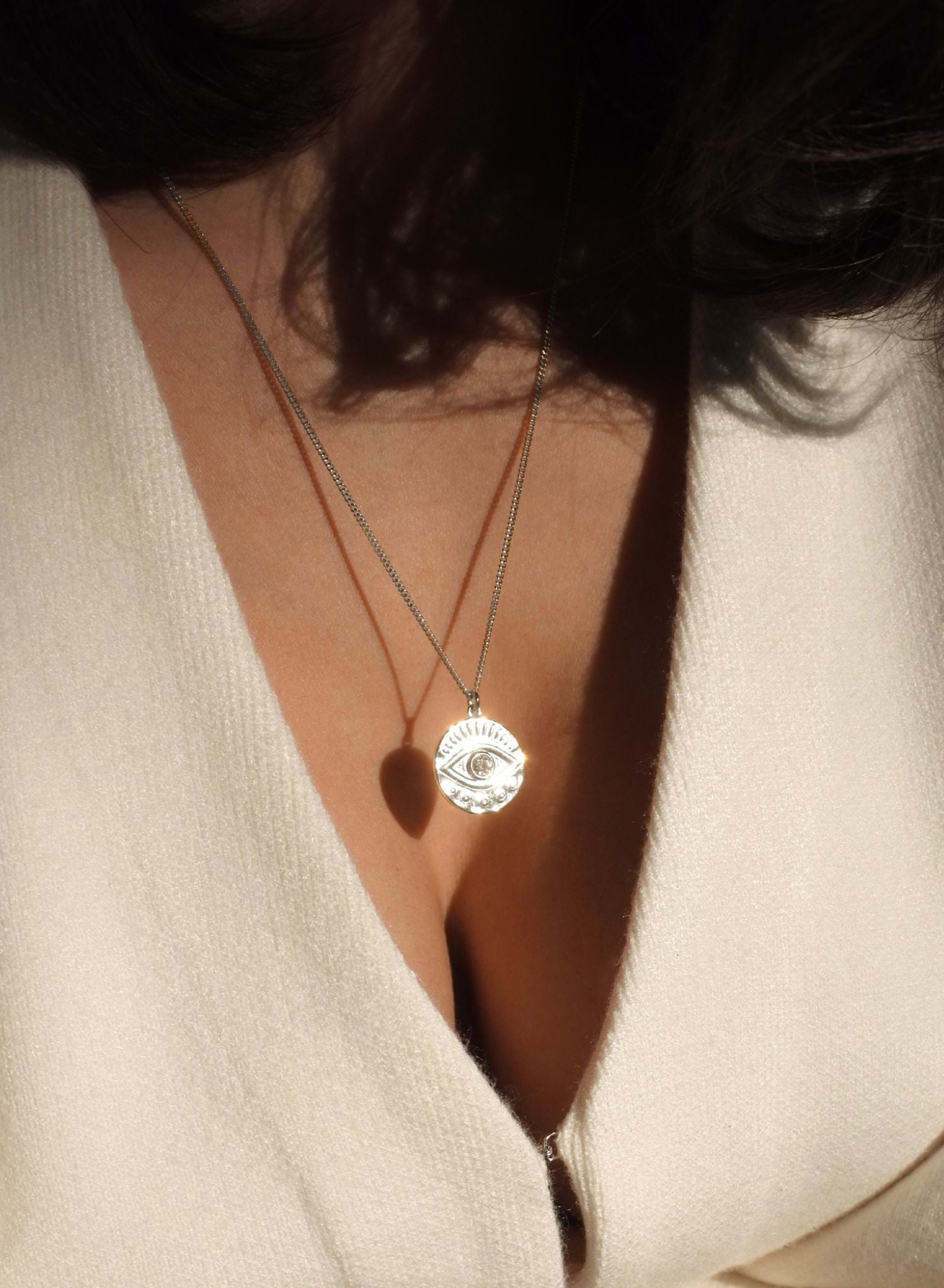 Notre collier Œil Protecteur est une incarnation moderne d'un talisman ancestral, enraciné dans les traditions qui s’étendent à travers les époques et les cultures du monde entier. Ce symbole dominé par un œil vigilant au centre représente une barrière contre les malveillances et un bouclier spirituel. Le dos du médaillon porte l'inscription "SAFE & DIVINELY PROTECTED", en français: "En sécurité et divinement protégée". Une affirmation de garde et de guidance spirituelle.